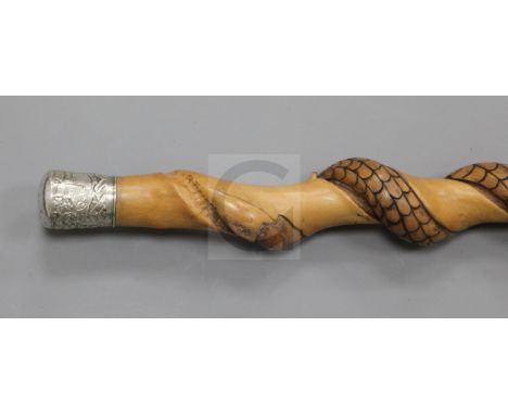 An Asian carved wooden serpent walking stick, with a Chinese silver knop, the handle decorated with figures in a continuous l