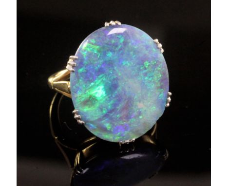 An 18ct gold and platinum set oval black opal dress ring, the stone measuring 20.5mm by 17.6mm, size L.