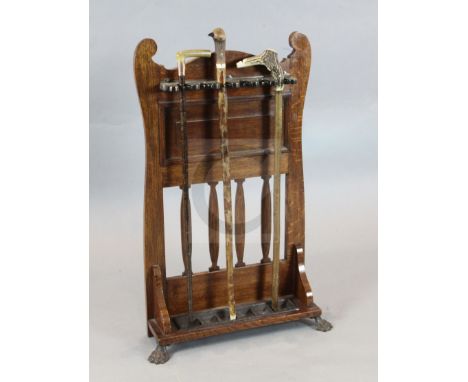 An Edwardian metal mounted oak stick stand, with turntable locking bar and three assorted walking sticks, width 1ft 10in. hei