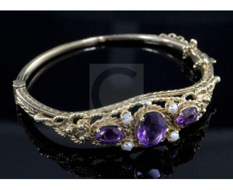 A 1970's Victorian style 9ct gold, amethyst and seed pearl set hinged bangle.