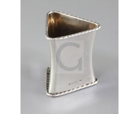 A 1930's Arts & Crafts silver waisted triangular napkin ring, by Omar Ramsden, hallmarked London 1938, hand hammered with rop