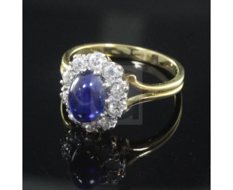 A cabochon sapphire and diamond cluster ring, the central sapphire surrounded by 10 brilliants, on 18ct gold pierced shank, s