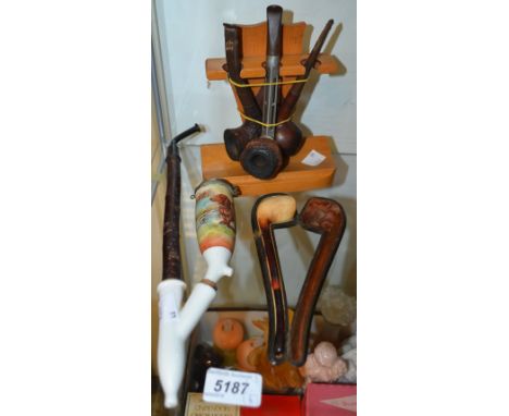 Smoking Interest - a treen pipe rack holding three pipes; a cased Meerschaum pipe; a German porcelain pipe, the bowl decorate