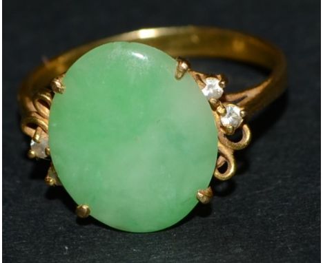 A lady's jade green stone and diamond dress ring, central oval jade green stone panel, between two white stone accented scrol