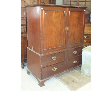 An early-19th century mahogany small linen press having a pair of panelled doors enclosing five slides above two small and on