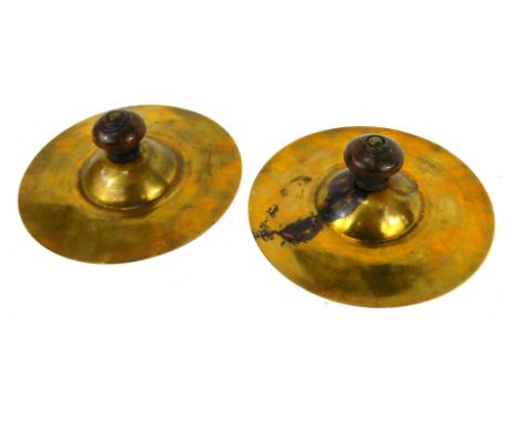 A pair of 1950s brass parade cymbals, with turned wooden handles, 18cm diameter.