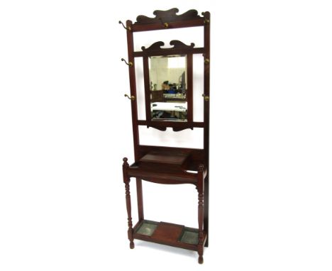 An early 20thC mahogany hall stand, the top with a scroll carved panel above an arrangement of seven brass hooks, with a cent