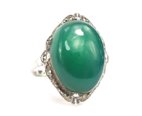 A silver and imitation jade dress ring, the oval jade coloured stone with outer wave design border set with marcasite, on whi