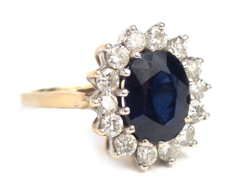 An 18ct gold sapphire and diamond cluster ring, with oval cut sapphire, 9.8mm x 7.8mm x 4.2mm, surrounded by fourteen round b