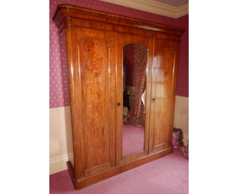 A Victorian mahogany triple wardrobe, the top with a moulded edge above three doors, the central door with a mirrored panel, 