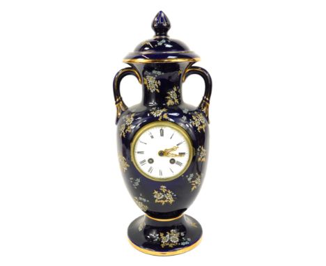 A French Severe style porcelain mantel clock, formed as a vase and cover, on navy blue ground, enamelled with flowers, and Ro