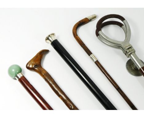 A collection of walking sticks and canes, to include a silver sleeved cane with green agate modular top, a novelty walking st