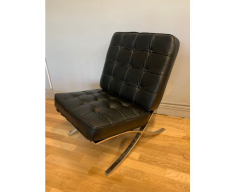 A contemporary Barcelona style chair, upholstered in black button back leather, raised on a polished steel frame with outswep