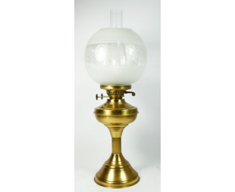 A brass column oil lamp, with frosted etched glass shade with chimney, raised on a circular stepped base. 54cm tall 