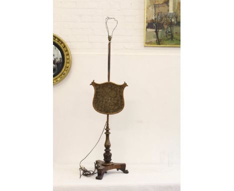 A carved wood pole screen on foliate carved vase form stem upon tripod base with volute foliate feet, the screen of shield fo