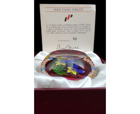 A Perthshire glass wild pansy paperweight, the pair of flowers floating on a ruby translucent ground within a ring of millefi
