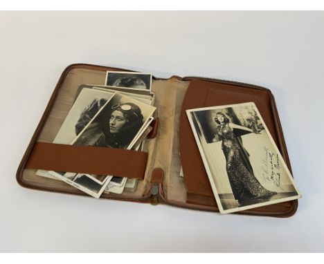 A tan leather case containing vintage photographs, some with facsimile signatures, including a photograph of the English pilo