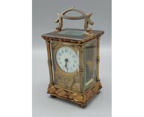 An Art Nouveau brass and ormolu cased carriage clock decorated with stylised flowers the circular enamelled dial with Arabic 