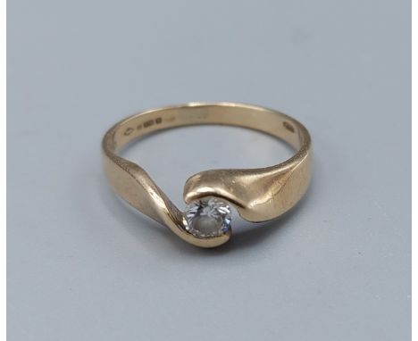 A 9ct gold solitaire diamond ring set with single diamond within a crossover setting, approx 0.15ct, ring size J, 2.2gms 