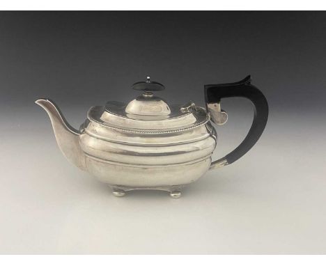 A George V silver teapot, of ovoid form, with gadrooned border, atop four bun feet, with ebonised handle and finial, height 1