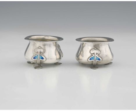 A pair of Edwardian Art Nouveau or Arts and Crafts silver and enamel salts, each of globular form, atop three pad feet, forme