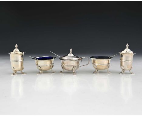 An Edwardian silver condiment set, comprising a pair of peppers, pair of salts with spoons, and mustard pot with ladle, the m