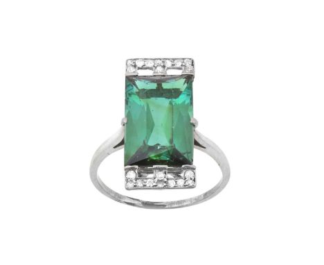 A Green Tourmaline and Diamond Ringthe oblong scissor cut tourmaline to sit vertically with a geometric motif inset with eigh