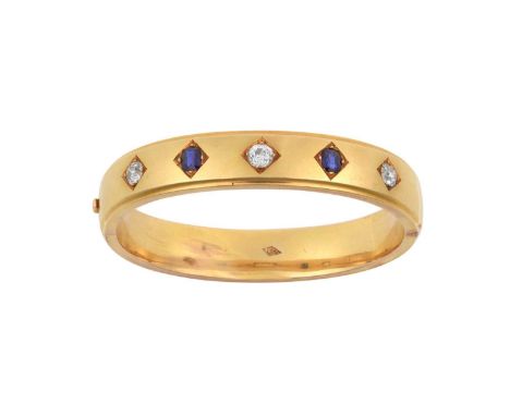 A Sapphire and Diamond Banglethe broad yellow plain polished bangle inset with three old cut diamonds alternating with two ov