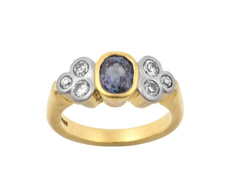 An 18 Carat Gold Alexandrite and Diamond Ringthe oval cut alexandrite in a yellow rubbed over setting, flanked by trios of ro