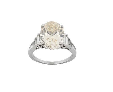 A Diamond Ringthe oval cut diamond in a white four claw setting, to stepped graduated baguette cut diamond set shoulders, on 