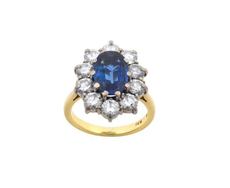 An 18 Carat Gold Sapphire and Diamond Cluster Ringthe oval cut sapphire within a border of round brilliant cut diamonds, in w