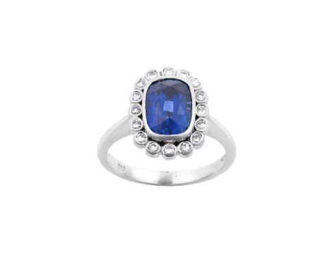 A Platinum Sapphire and Diamond Cluster Ringthe cushion cut sapphire within a border of round brilliant cut diamonds, in rubb