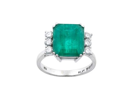 An 18 Carat White Gold Emerald and Diamond Ring the emerald-cut emerald in a double claw setting, flanked by trios of round b