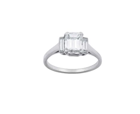 A Diamond Three Stone Ringan emerald-cut diamond between two baguette cut diamonds, in white claw and channel settings, to a 