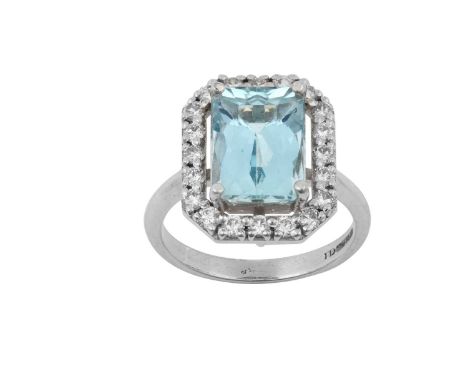 An 18 Carat White Gold Aquamarine and Diamond Cluster Ringthe rectangular scissor cut aquamarine within a spaced border of ro