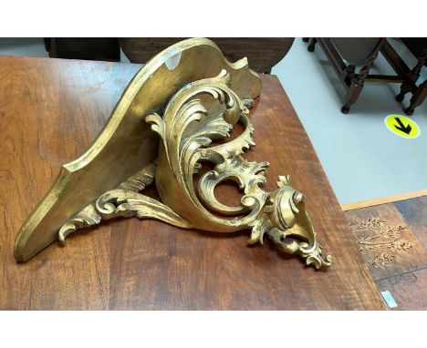 A rococo style gilt wall shelf; a pair of gilt gesso candlesticks 