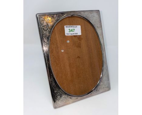 A chased silver photo frame, rectangular with oval aperture, import marks, height 20 cm; a black lacquer snuff box with pewte