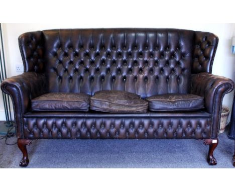 A BROWN LEATHER BUTTON UPHOLSTERED WING BACK SETTEE with claw and ball feet, 190cm wide x 88cm deep x 103cm high