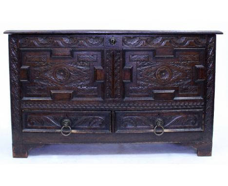 AN OLD OAK MULE CHEST with carved decoration to the top and front and with two drawers and above bracket feet 128cm wide x 49
