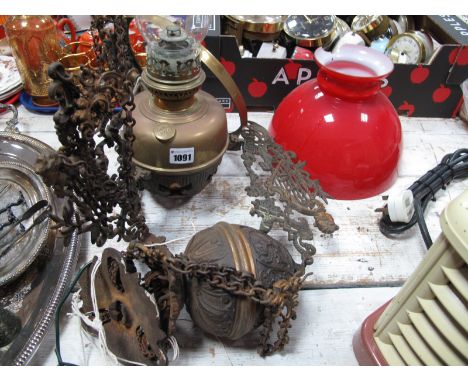 An Ornate Hanging Ceiling Oil Lamp, with weighted baluster, pierced support to red glass shade. (Damaged)