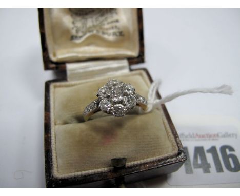 A Diamond Cluster Ring, of flowerhead design, claw set with old cut stones, between inset shoulders.