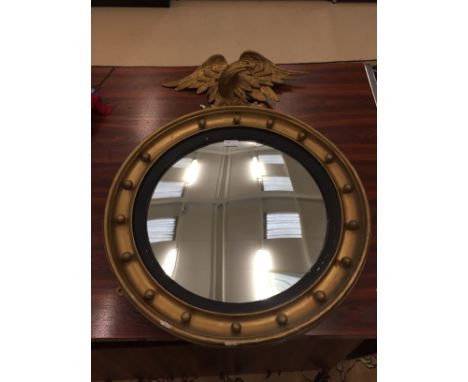 A circular gilt mirror with eagle finial