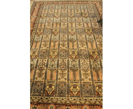 A Persian carpet, the central panel set with tiled design and each tile with floral motifs, within a stepped salmon pink and 