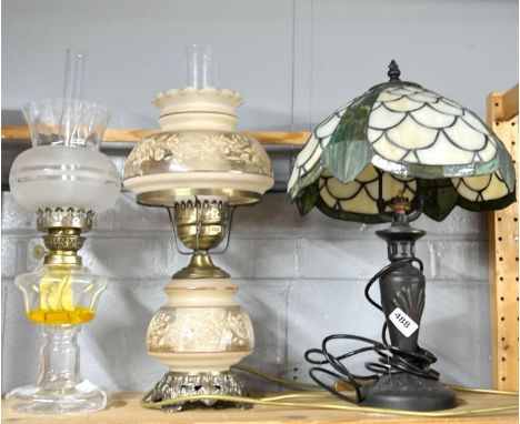 A Tiffany style table lamp and shade, H. 49cm. Together with an oil lamp style table lamp and a further oil lamp.