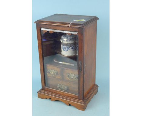 An early 20th Century oak smokers cabinet with thee drawers, ceramic lidded tobacco jar and spare pipe, with working lock and