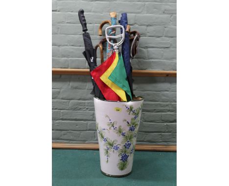 A large ceramic stick/umbrella stand with contents including shooting sticks