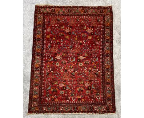 A Kashan style carpet with bird and foliate decoration across a burgundy field within boteh and flowerhead multiple borders. 
