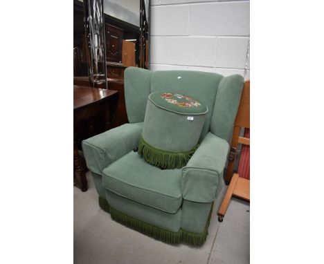 A vintage wingback armchair and woolwork top footstool