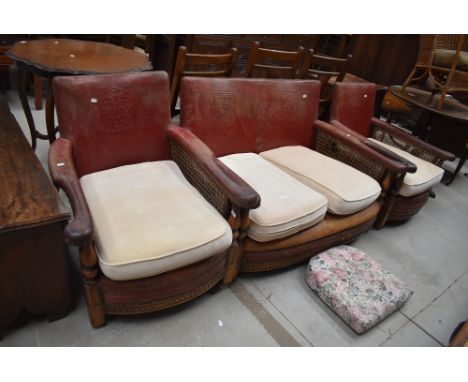 An early Ercol Arts and Crafts three piece suite having embossed leather back, bergere cane sides, and oak frame, understood 
