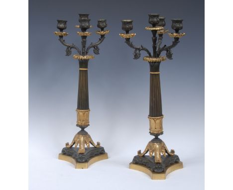 A pair of French Empire design gilt and dark patinated three-branch four-light candelabra, lotus grasped sconces and pillars,